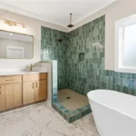 Primary suite bathroom with dual vanities, designer tile, and spacious layout in new Brown Summit home by Lakenridge Builders Inc.