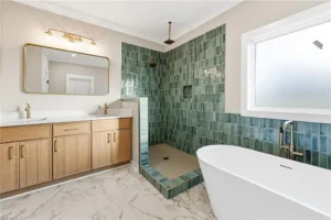 Primary suite bathroom with dual vanities, designer tile, and spacious layout in new Brown Summit home by Lakenridge Builders Inc.